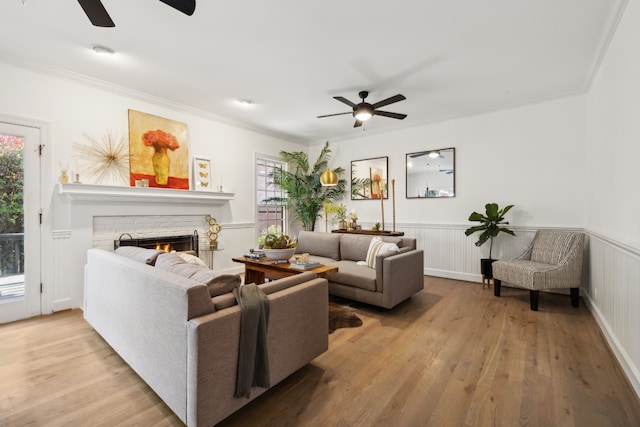 living room featuring a fireplace, light hardwood / wood-style floors, a healthy amount of sunlight, and ornamental molding