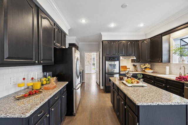 kitchen featuring ornamental molding, stainless steel appliances, backsplash, light stone countertops, and light hardwood / wood-style flooring