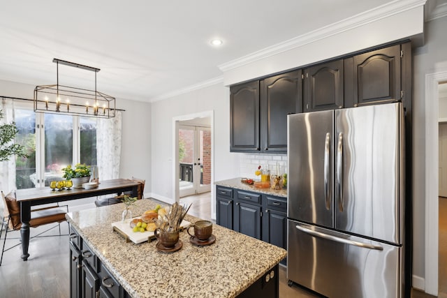 kitchen with stainless steel refrigerator, backsplash, hanging light fixtures, crown molding, and a kitchen island