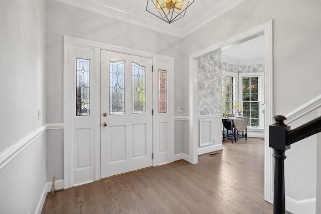 entrance foyer featuring hardwood / wood-style floors, a chandelier, and ornamental molding