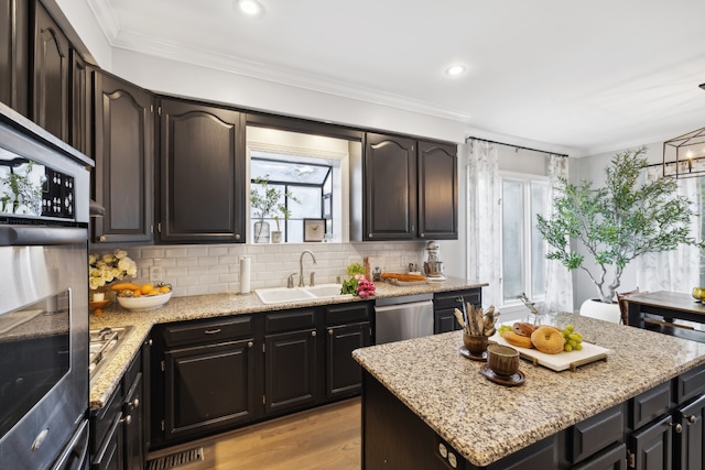 kitchen featuring light stone countertops, appliances with stainless steel finishes, sink, and crown molding