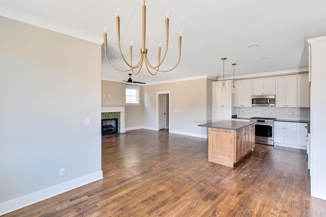 kitchen with stainless steel appliances, a center island, tasteful backsplash, ornamental molding, and decorative light fixtures