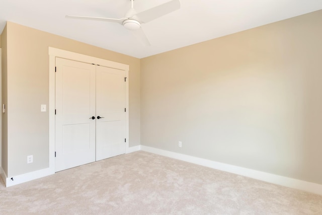 unfurnished bedroom featuring light carpet, a closet, and ceiling fan