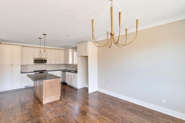 kitchen featuring backsplash, hanging light fixtures, ornamental molding, a center island, and stainless steel appliances