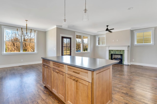 kitchen featuring crown molding, decorative light fixtures, light brown cabinets, dark hardwood / wood-style floors, and a fireplace