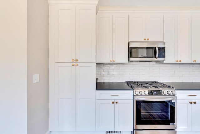 1297 Thomas Ave, Chattanooga, TN 37409 - kitchen featuring stainless steel appliances, dark countertops, decorative backsplash, and white cabinets