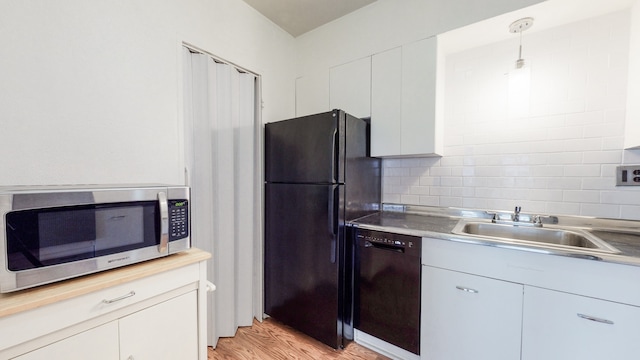 kitchen featuring black appliances, light wood-type flooring, white cabinets, pendant lighting, and decorative backsplash