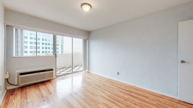 unfurnished room featuring light hardwood / wood-style floors and an AC wall unit