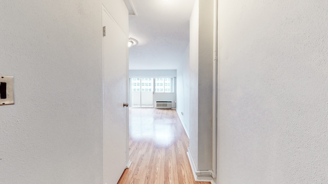 hall featuring light wood-type flooring and an AC wall unit