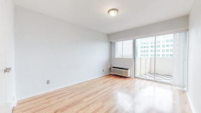 unfurnished room with a wall unit AC and light wood-type flooring