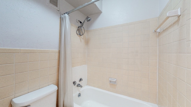 bathroom featuring tile walls, shower / bath combo, and toilet