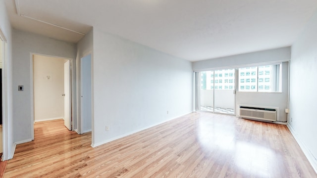 empty room with light wood-type flooring and a wall mounted air conditioner