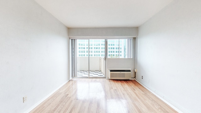 unfurnished room with a wall unit AC and light hardwood / wood-style floors