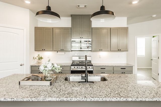 kitchen with stainless steel appliances, light stone counters, pendant lighting, and decorative backsplash