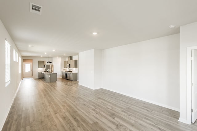 unfurnished living room featuring wood-type flooring and sink