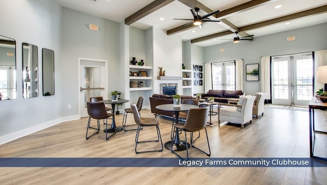 living room with french doors, a fireplace, light hardwood / wood-style floors, beamed ceiling, and ceiling fan