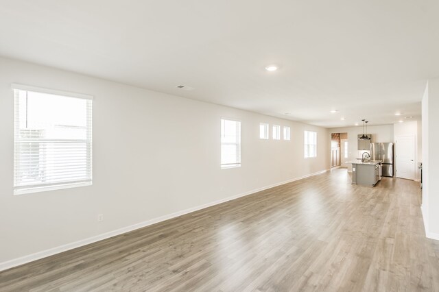 unfurnished living room featuring light hardwood / wood-style floors and sink