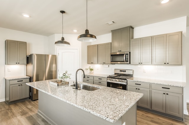 kitchen with dark hardwood / wood-style flooring, light stone counters, sink, appliances with stainless steel finishes, and decorative light fixtures