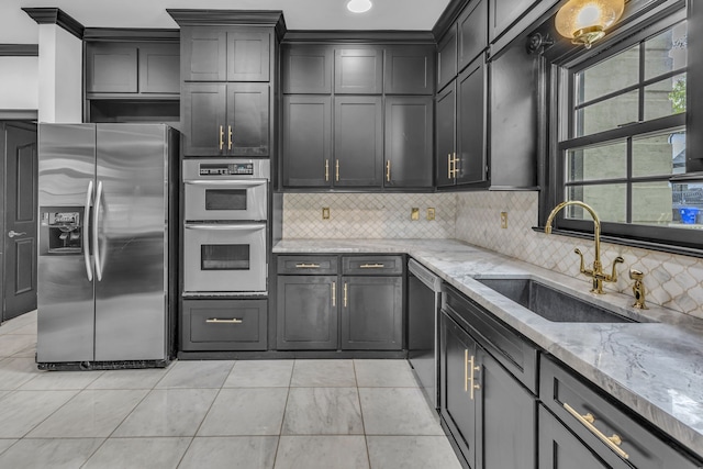 kitchen featuring light stone counters, stainless steel appliances, backsplash, light tile patterned floors, and sink