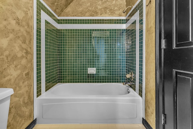 bathroom with toilet, tiled shower / bath, and tile patterned flooring