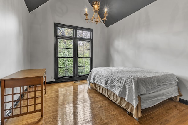 bedroom with an inviting chandelier, hardwood / wood-style floors, and vaulted ceiling