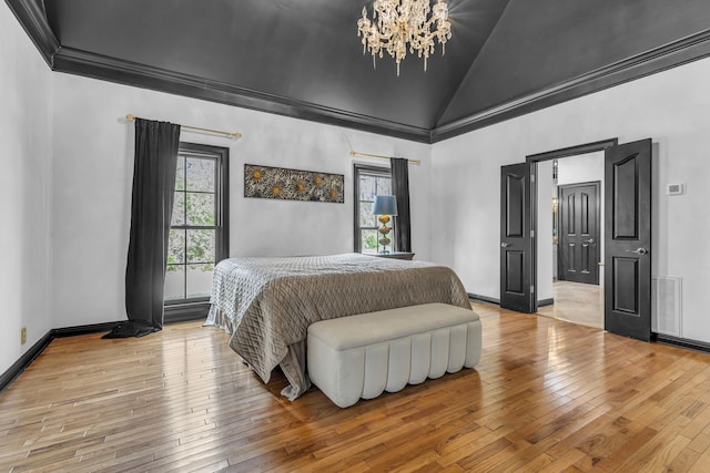 bedroom featuring light hardwood / wood-style floors, a chandelier, lofted ceiling, and ornamental molding