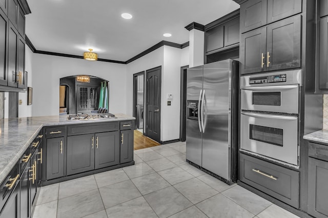 kitchen with light stone countertops, light tile patterned floors, crown molding, and stainless steel appliances