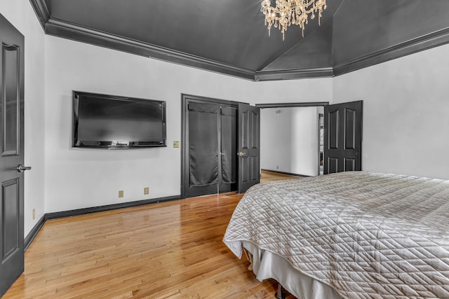 bedroom featuring lofted ceiling, hardwood / wood-style floors, a notable chandelier, and crown molding