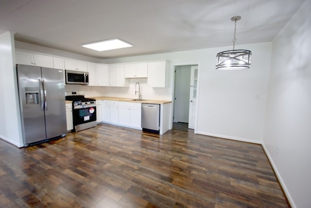 kitchen with white cabinetry, stainless steel appliances, dark hardwood / wood-style floors, and decorative light fixtures