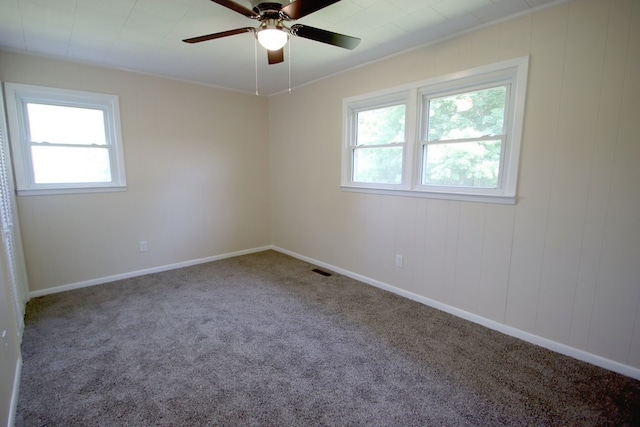 carpeted spare room featuring ornamental molding, a wealth of natural light, and ceiling fan