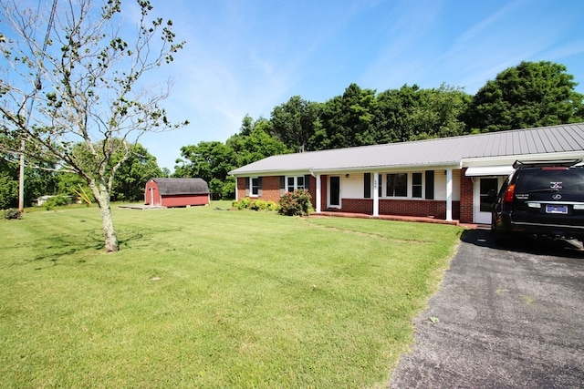 ranch-style home with a front lawn, a storage unit, and covered porch