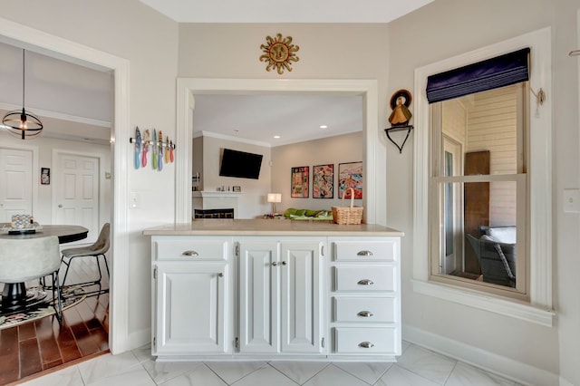 interior space with white cabinets, hanging light fixtures, and crown molding