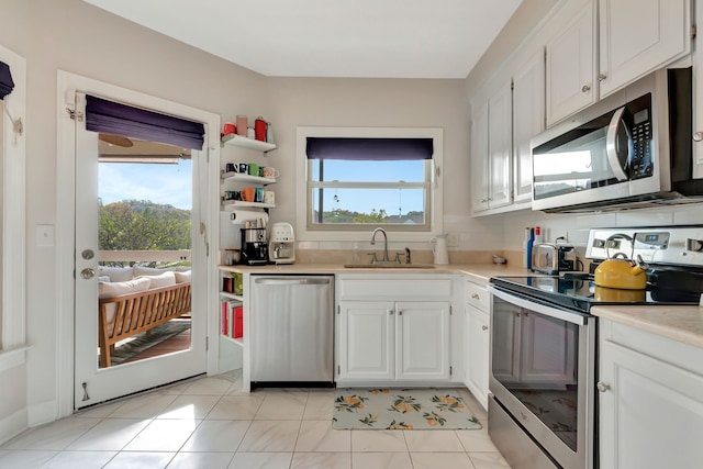 kitchen with white cabinetry, stainless steel appliances, sink, and light tile patterned floors