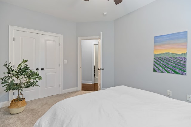 bedroom with ceiling fan, light carpet, and a closet