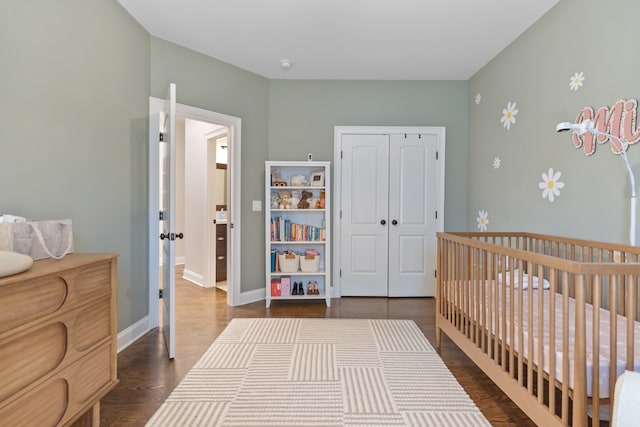 bedroom with dark hardwood / wood-style flooring, a closet, and a nursery area