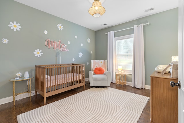 bedroom featuring a crib and dark hardwood / wood-style floors