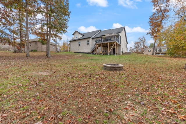 rear view of house featuring a yard, a fire pit, and a wooden deck