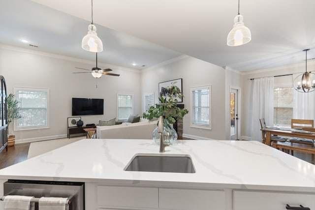 kitchen with a wealth of natural light, decorative light fixtures, and a kitchen island with sink