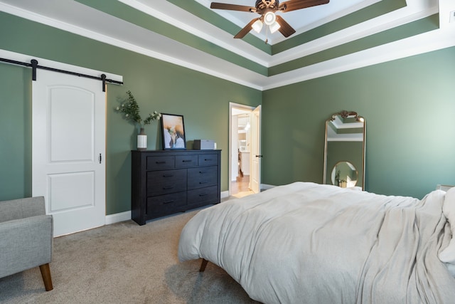 carpeted bedroom featuring a barn door, ceiling fan, a raised ceiling, and ornamental molding