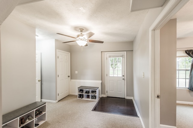 carpeted entryway with a textured ceiling and ceiling fan