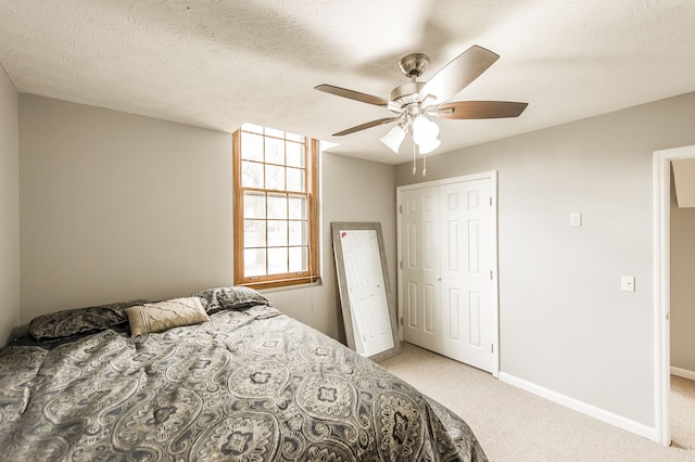 carpeted bedroom with a textured ceiling, ceiling fan, and a closet