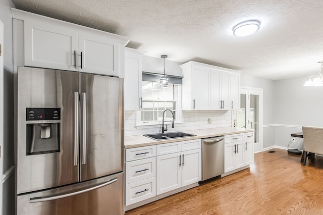 kitchen with pendant lighting, white cabinetry, and appliances with stainless steel finishes