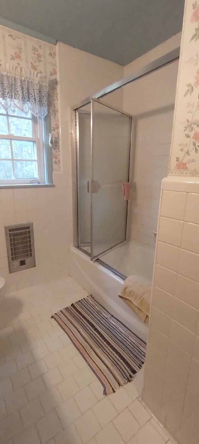 bathroom featuring a shower with door, tile patterned floors, and heating unit