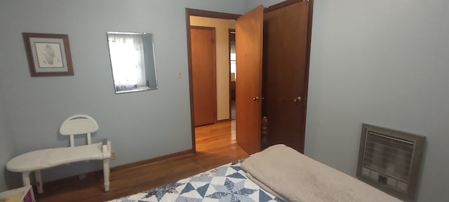 bedroom with hardwood / wood-style floors and heating unit