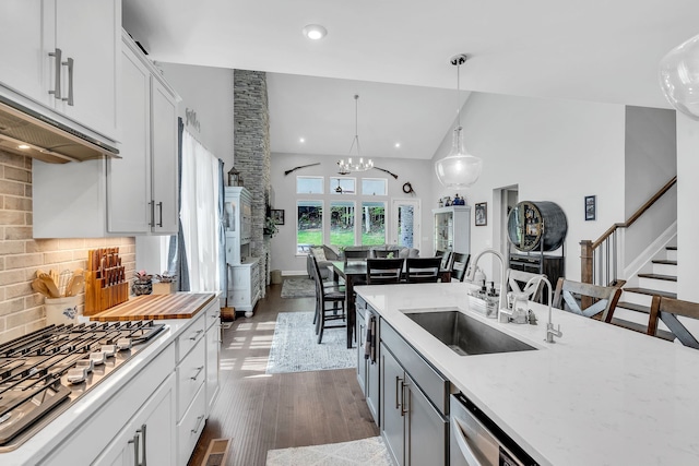 kitchen featuring stainless steel appliances, dark wood-type flooring, white cabinets, sink, and pendant lighting