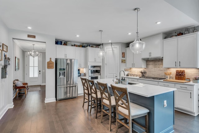 kitchen with a kitchen island with sink, appliances with stainless steel finishes, white cabinets, and dark hardwood / wood-style flooring