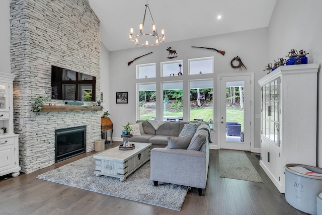 living room featuring dark wood-type flooring, high vaulted ceiling, a chandelier, and a stone fireplace