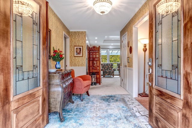 carpeted entryway featuring a wainscoted wall, ornamental molding, and wallpapered walls