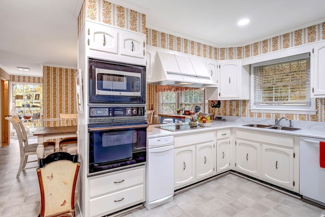 kitchen with ventilation hood, a sink, black appliances, and wallpapered walls