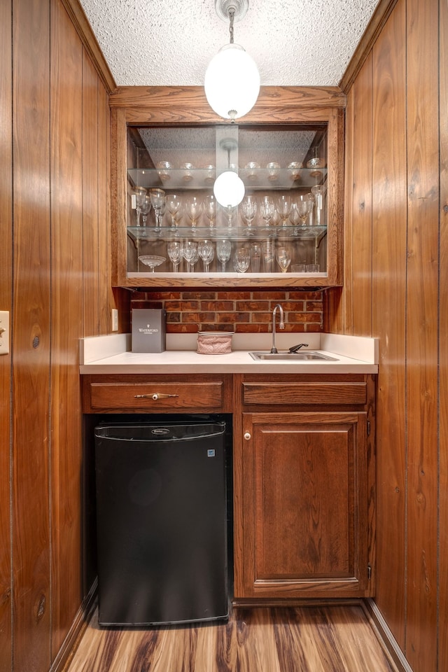 bar with wood finished floors, wood walls, indoor wet bar, and a sink